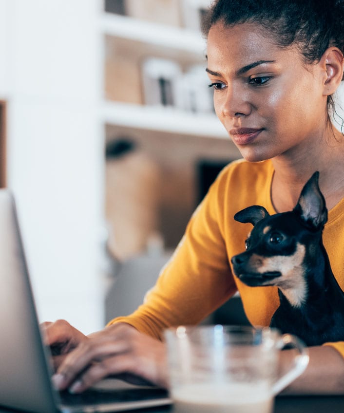 A woman working from home securely with her dog by her side using a VPN for Mac.